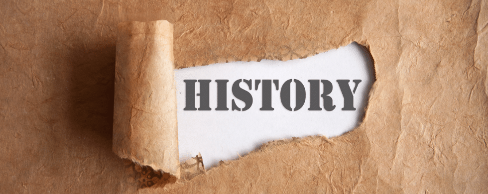 A ripped piece of brown paper with the word "History" behind it. C. Woods Company in Tyler, TX.