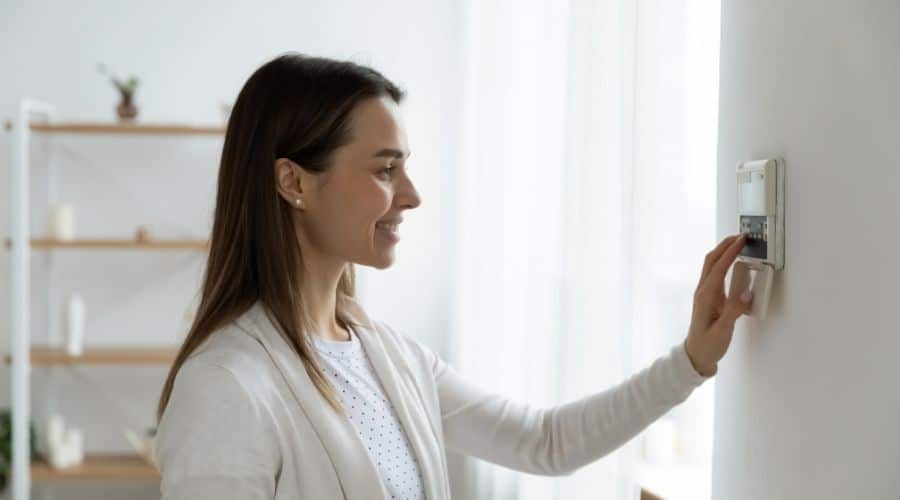 A woman adjusting the temperature on a thermostat installed by C. Woods Company in Tyler, TX.