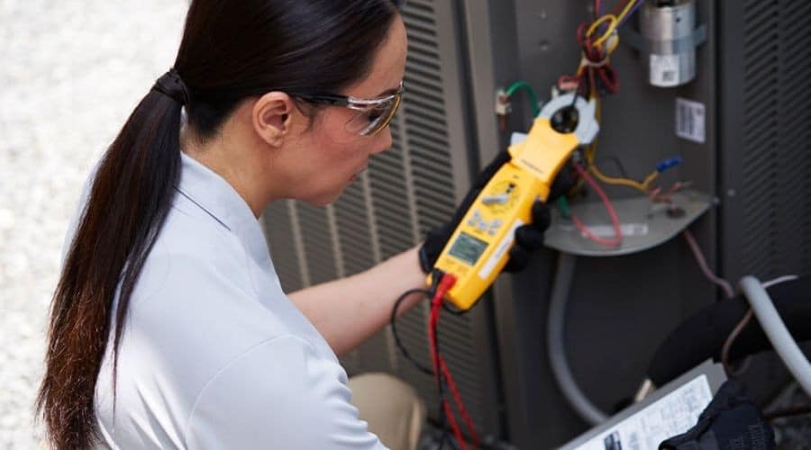 An HVAC tech from C. Woods Company in Tyler, TX performing maintenance on an AC unit