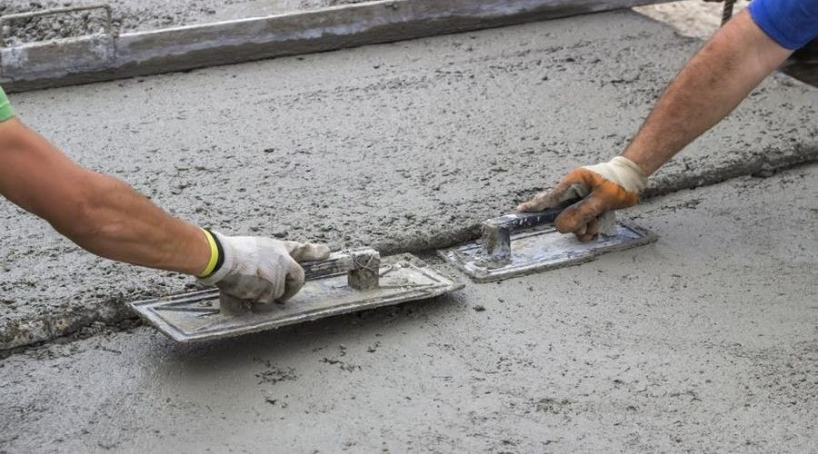 Two men smoothing fresh concrete. Call C. Woods Company for home services in Tyler TX