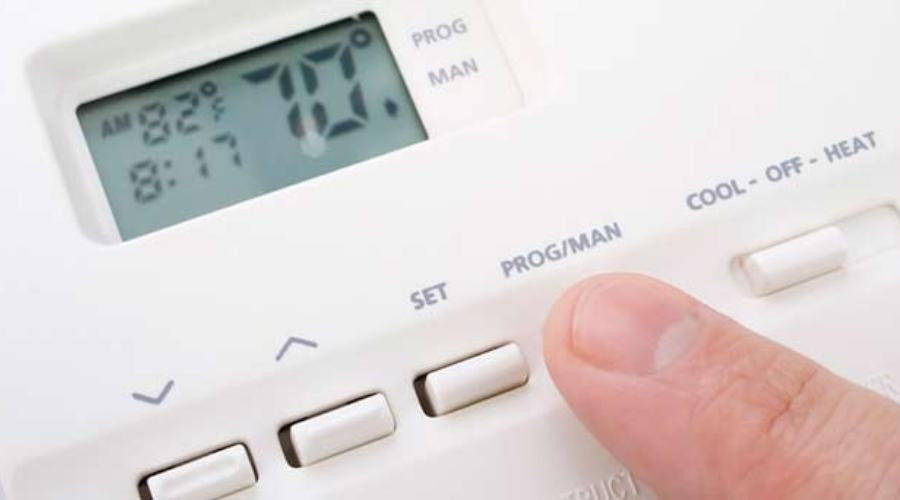 A man adjusting the temperature on a thermostat installed by C. Woods Company in Tyler, TX.