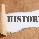 A ripped piece of brown paper with the word "History" behind it. C. Woods Company in Tyler, TX.