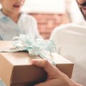 A little girl giving her father a gift box with a blue bow. C. Woods Company for HVAC service in TX