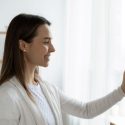 A woman adjusting the temperature on a thermostat installed by C. Woods Company in Tyler, TX.