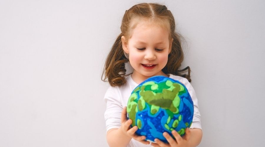 A little girl with pig tails holding a ball of the earth in Tyler TX
