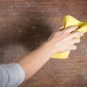 A woman cleaning dust off a desk. Call C. Woods Company in Tyler, TX for indoor air quality services