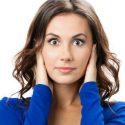 A woman with dark hair and a blue shirt covering her ears.