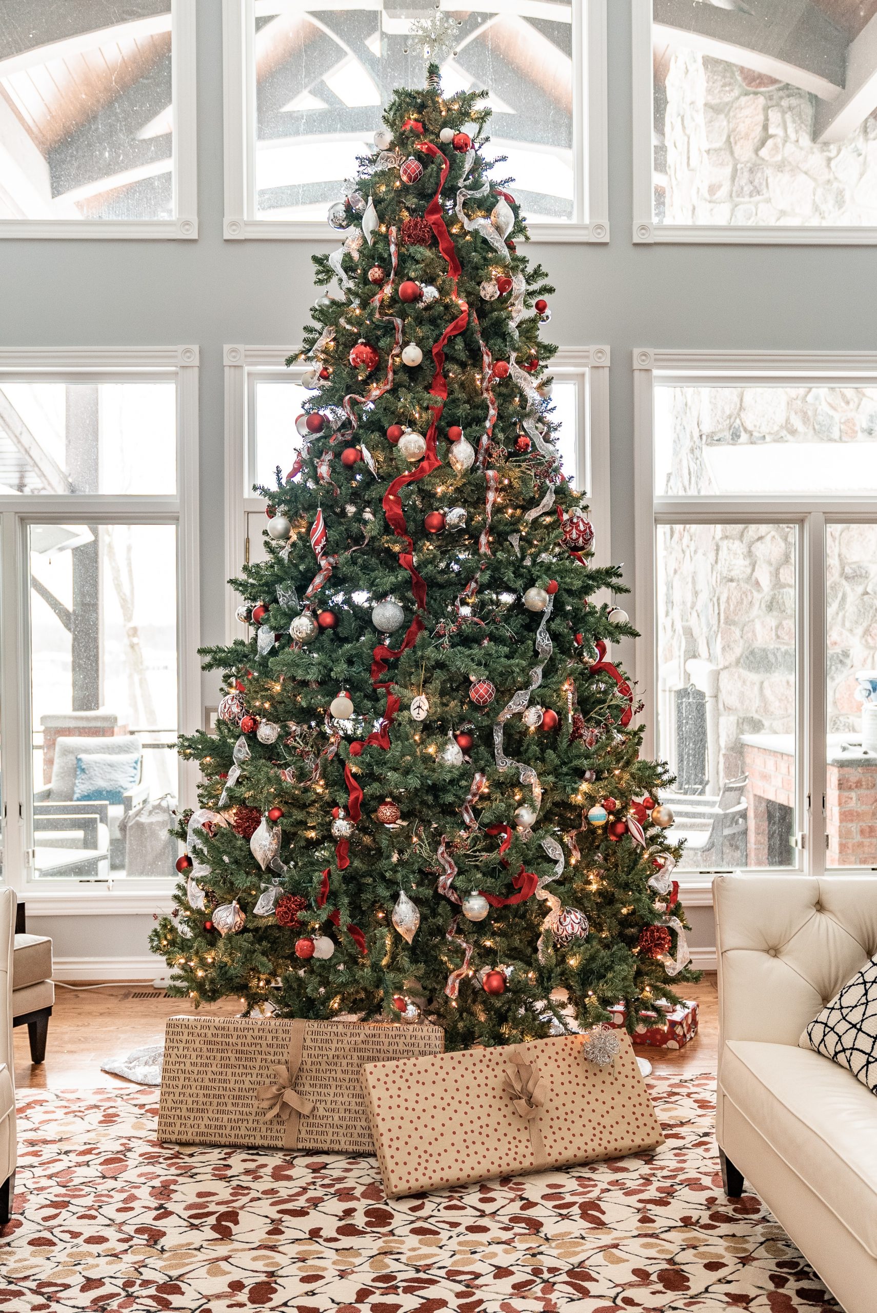 A large decorated Christmas tree in front of tall windows in a home in Tyler TX