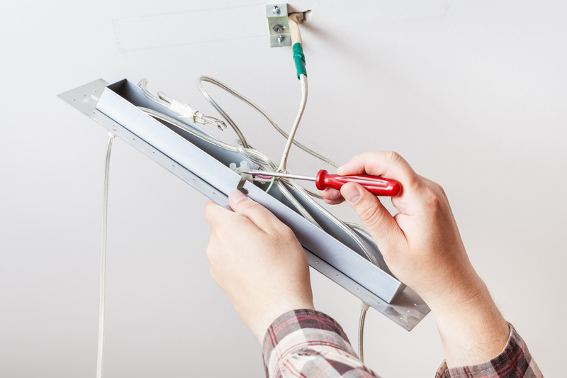 Electrician from C. Woods Company repairing a light in Tyler, TX