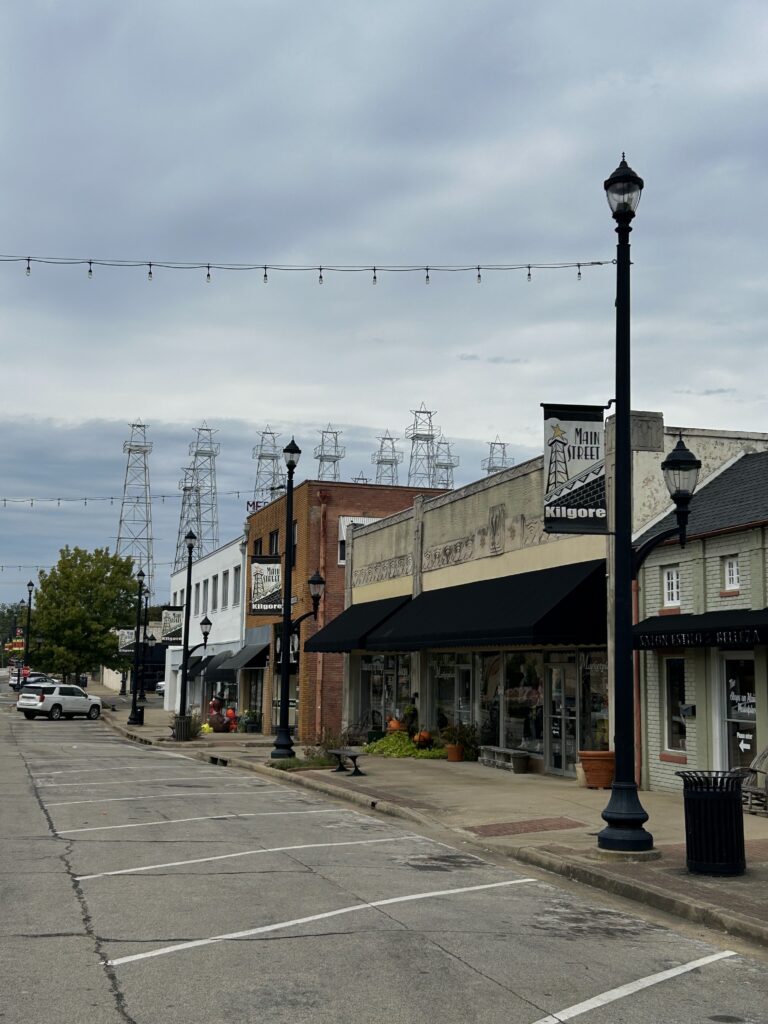 The Kilgore, Texas, downtown, including a street sign with the town name listed and a sidewalk with multiple storefronts
